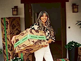 Woman holding a Bloomscape box outside of an open doorway